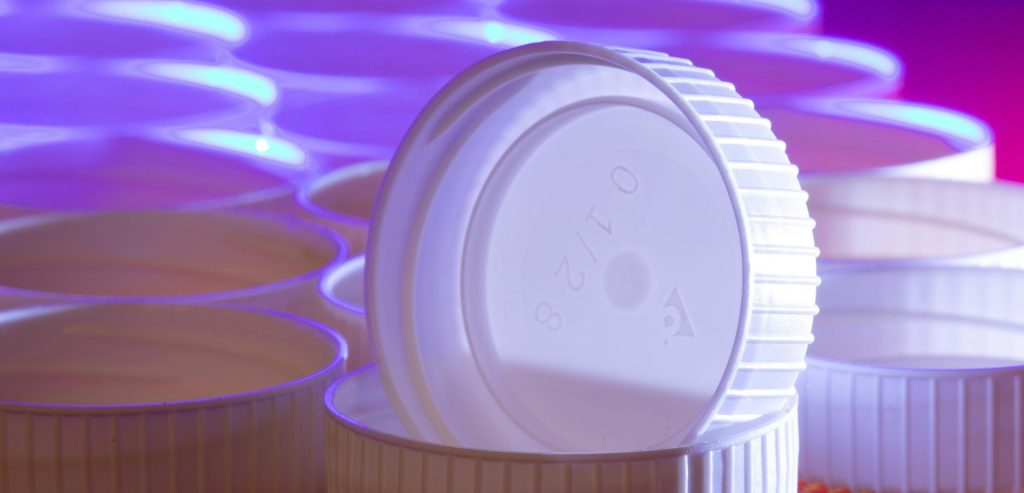 Aesthetic arrangement of white plastic lids with striking blue and purple lighting.